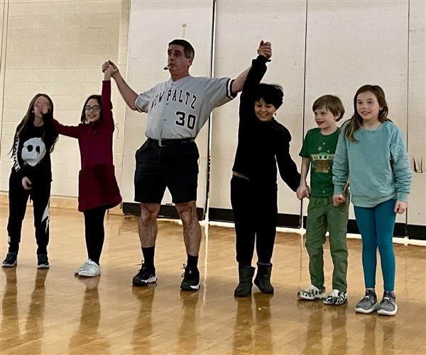  man standing with students holding hands up 